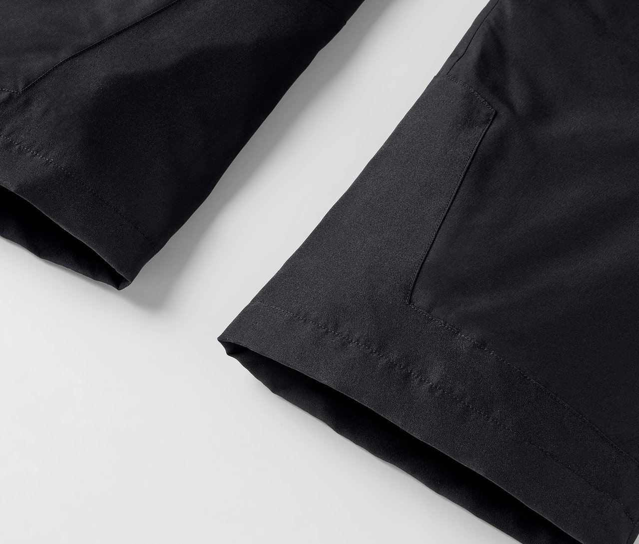 Detailaufnahme einer schwarzen Hose mit Tasche auf weißem Hintergrund.