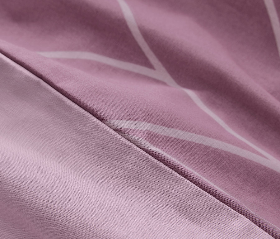 Detail einer lila Bettwäsche mit weißen geometrischen Mustern.