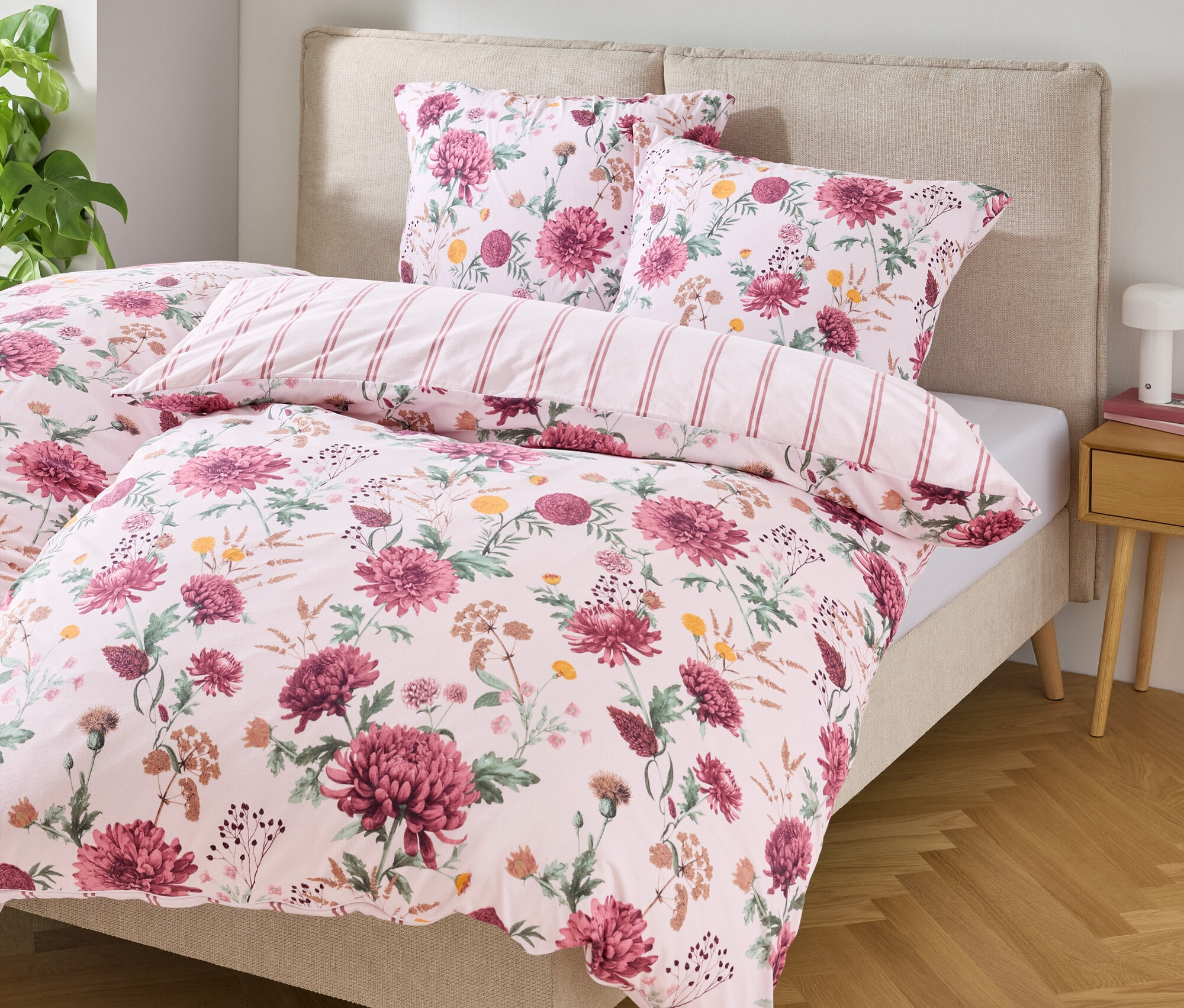 Bett mit blumengemusterter Bettwäsche und zwei Kissen.