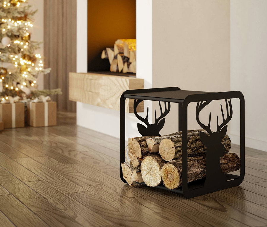 Ein schwarzer Eglo Sacol Holzaufbewahrung mit Hirschmotiven, gefüllt mit Holzscheiten, steht auf einem Holzboden neben einem Weihnachtsbaum.