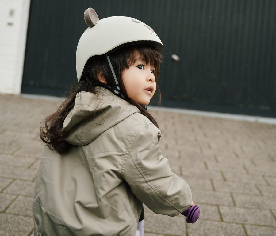 Mädchen auf lila Fahrrad mit HUDORA Kinderhelm, Beary, 44–47 cm.