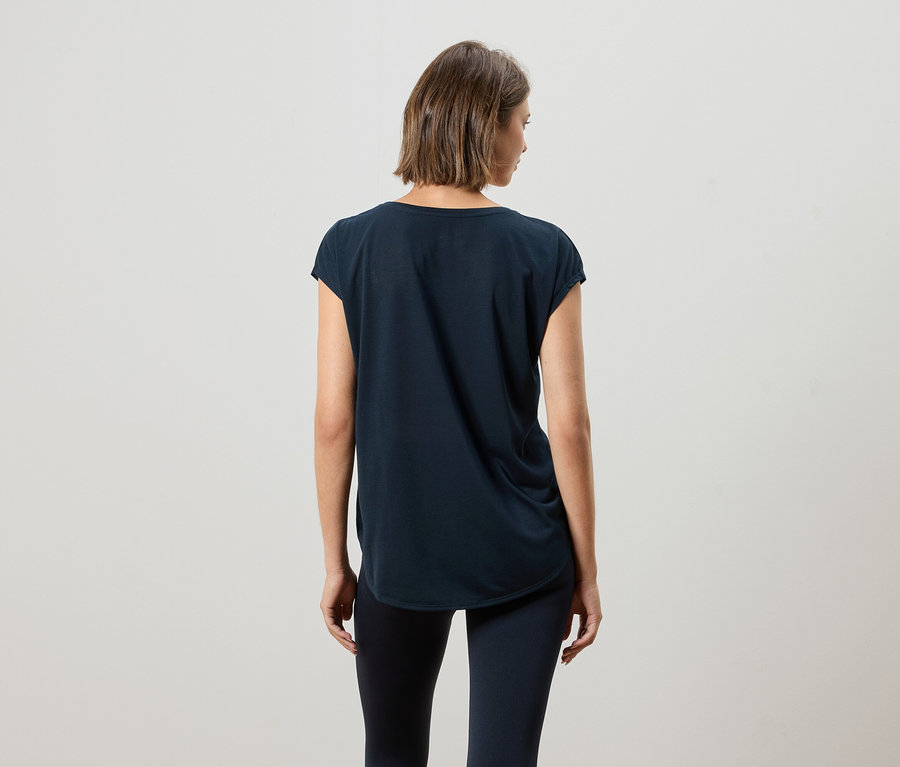 Rückansicht einer Frau mit kurzem braunen Haar, die ein dunkelblaues T-Shirt und Leggings trägt.