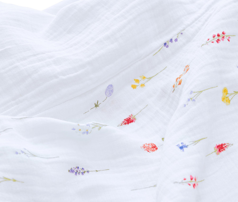 Nahaufnahme eines weißen Musselinstoffs mit kleinen bunten Blumenmustern.