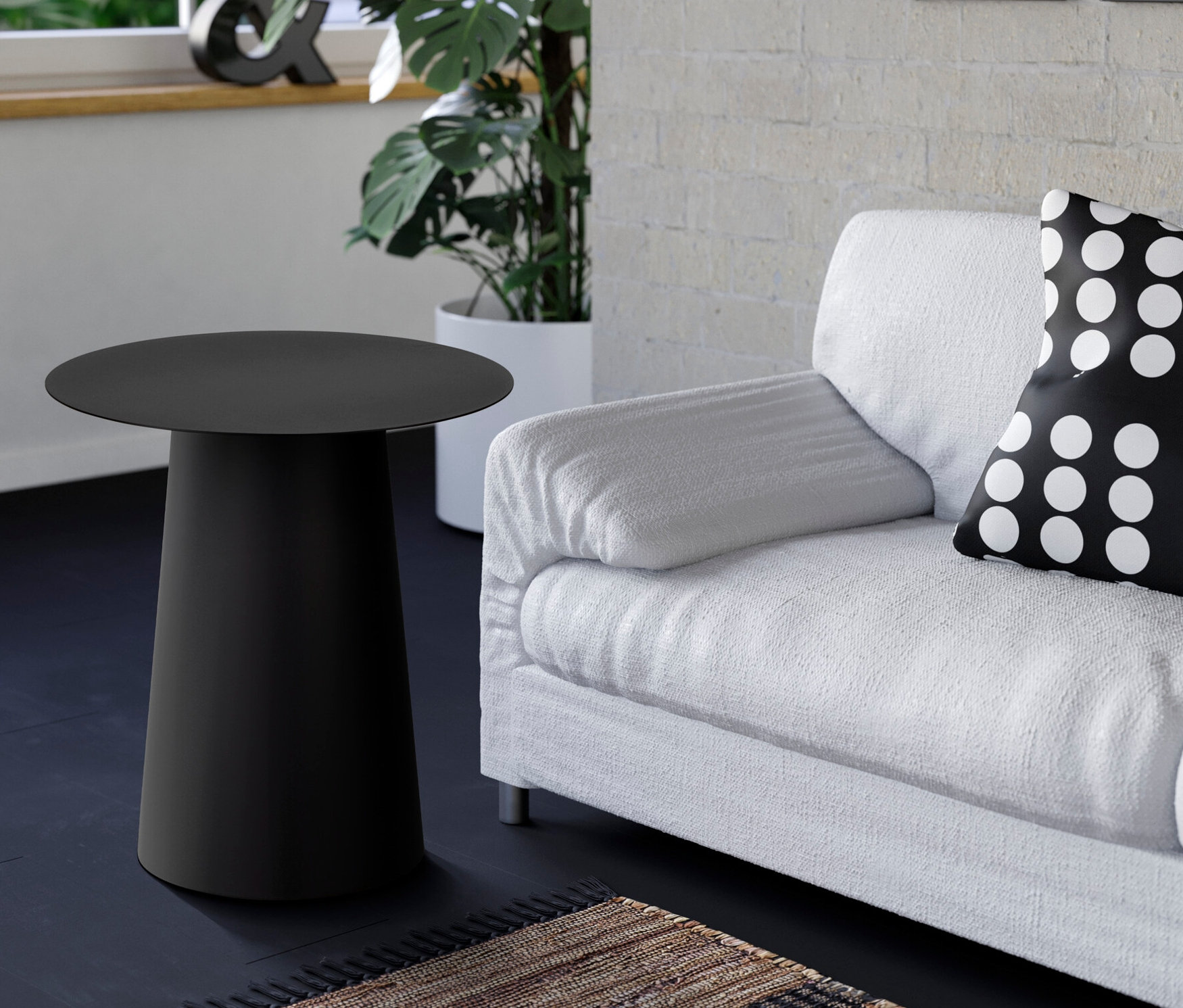 Schwarzer Beistelltisch neben einem weißen Sofa mit einem schwarz-weiß gepunkteten Kissen.