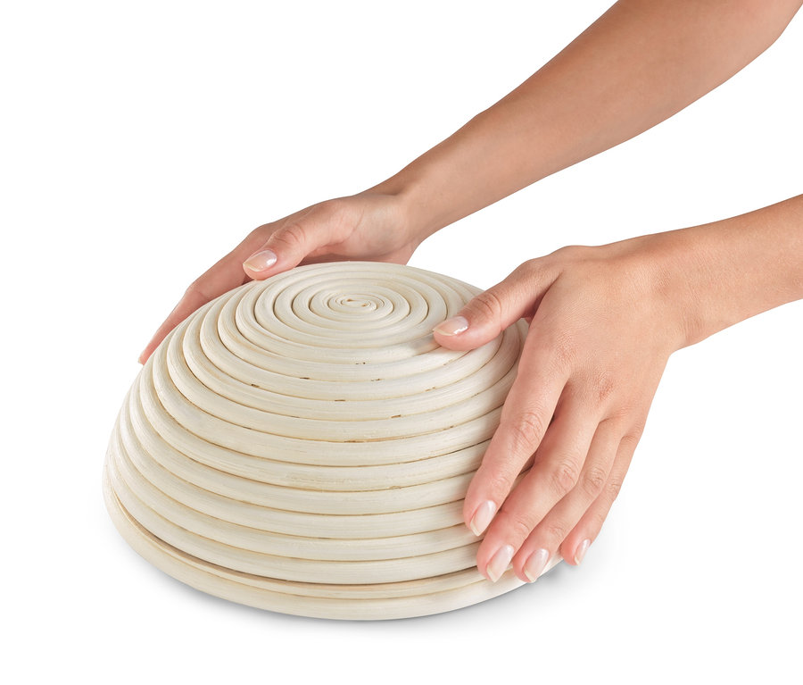 Zwei Hände halten ein rundes Gärkörbchen.