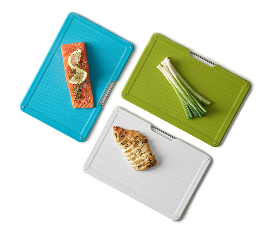 Lachs mit Zitrone auf blauem Joseph Joseph Schneidebrett-Set »Folio Slim«, Frühlingszwiebeln auf grünem und Hähnchen auf weißem Brett.