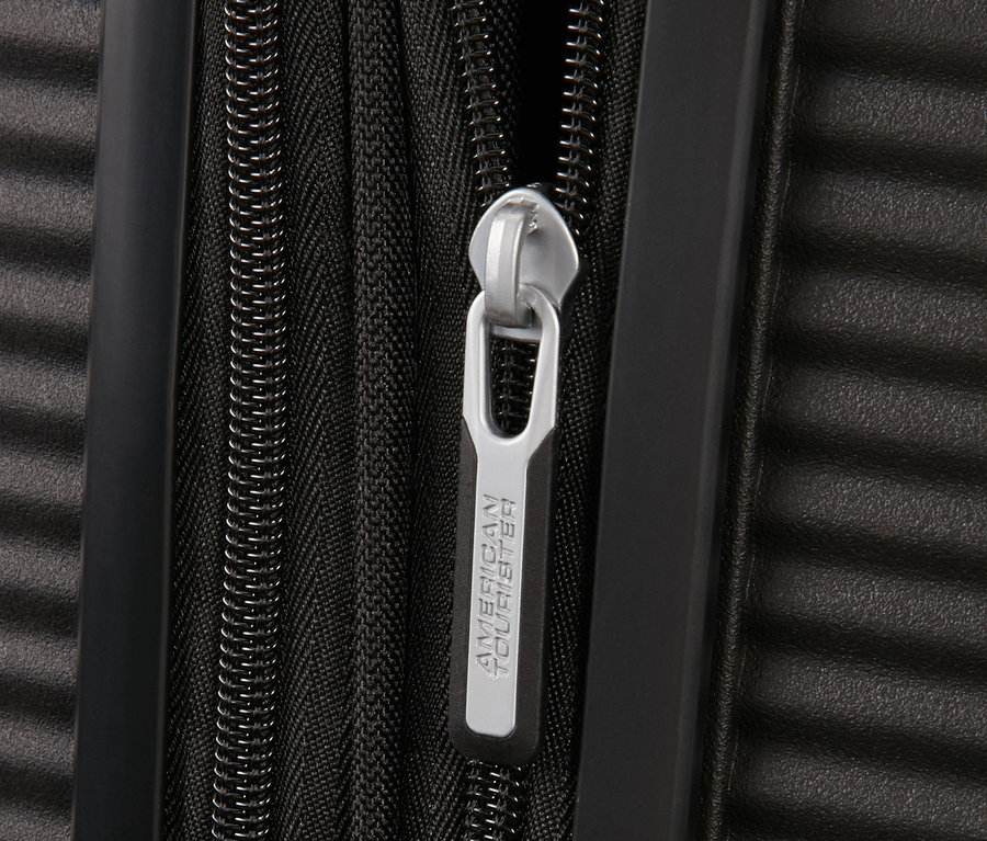 Detailaufnahme des Reißverschlusses eines schwarzen American Tourister Hartschalen-Koffers »Soundbox«.