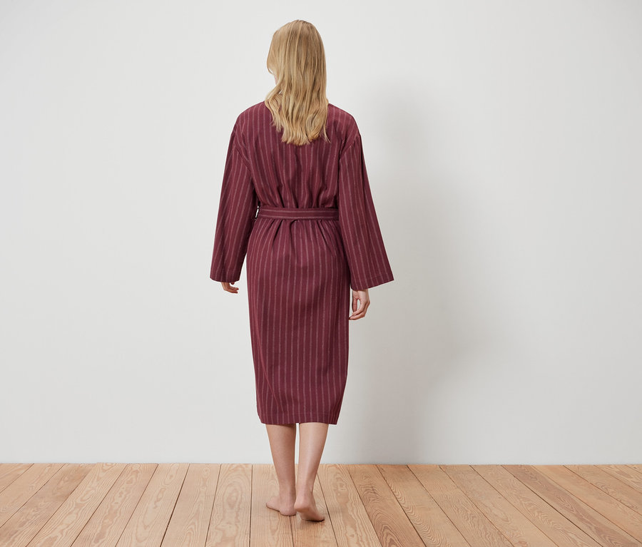 Frau trägt einen gestreiften Bademantel, von hinten gesehen.