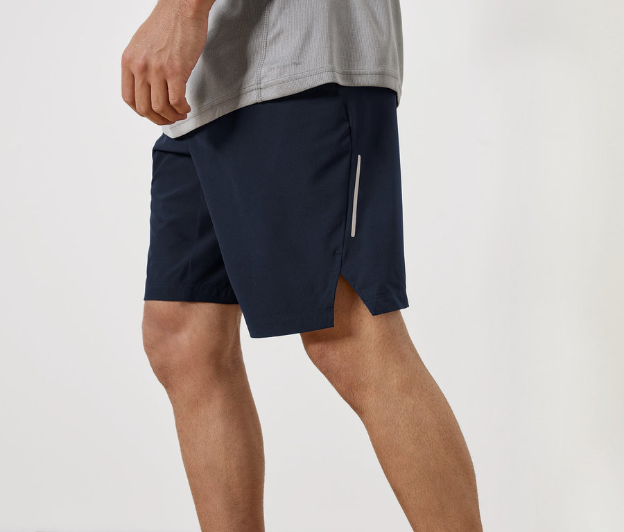 Ein Mann trägt dunkelblaue Shorts und ein graues T-Shirt.