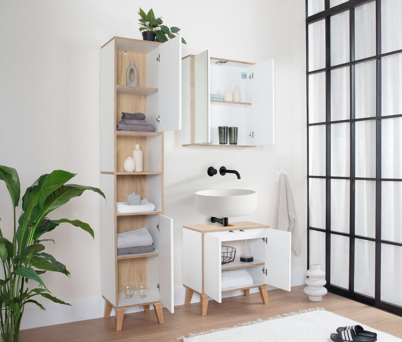 Ein Badezimmer zeigt einen grauen Roba Hochschrank »Morena« mit zwei Türen und zwei offenen Fächern neben einem weißen Roba Waschbeckenunterschrank »Morena« mit zwei Türen.