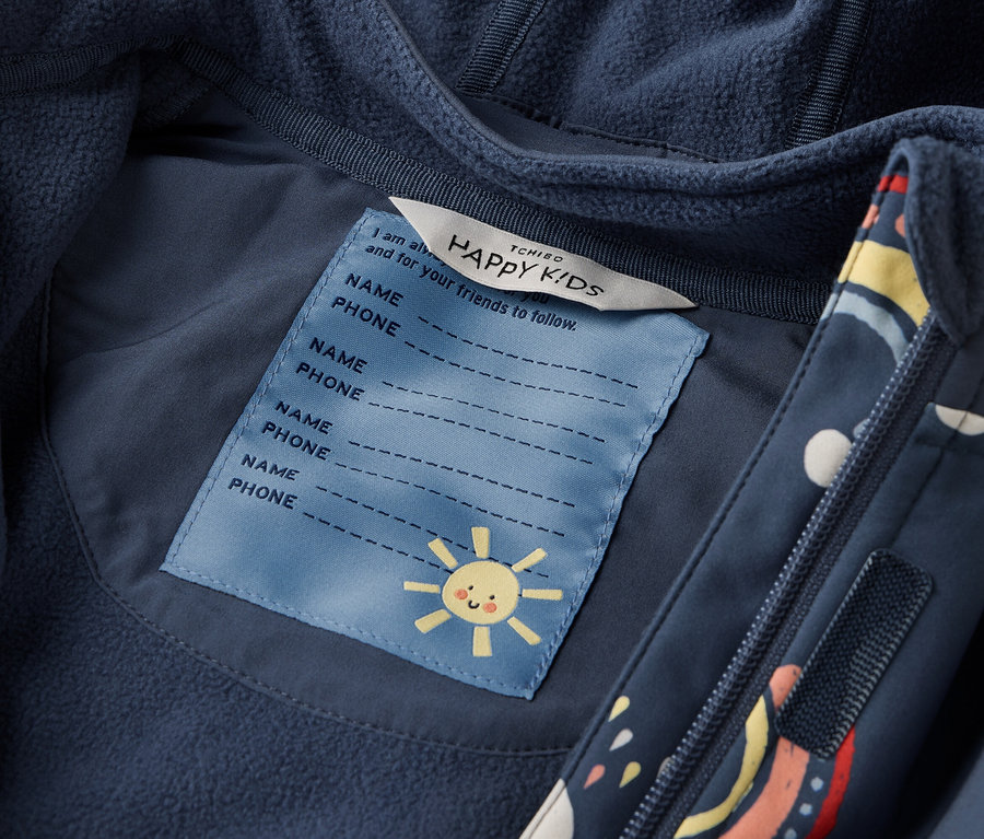 Detailaufnahme einer marineblauen Tchibo HAPPY KIDS Jacke mit Kapuze und Reißverschluss. Ein Etikett mit Namensfeldern und einer kleinen Sonne ist sichtbar.