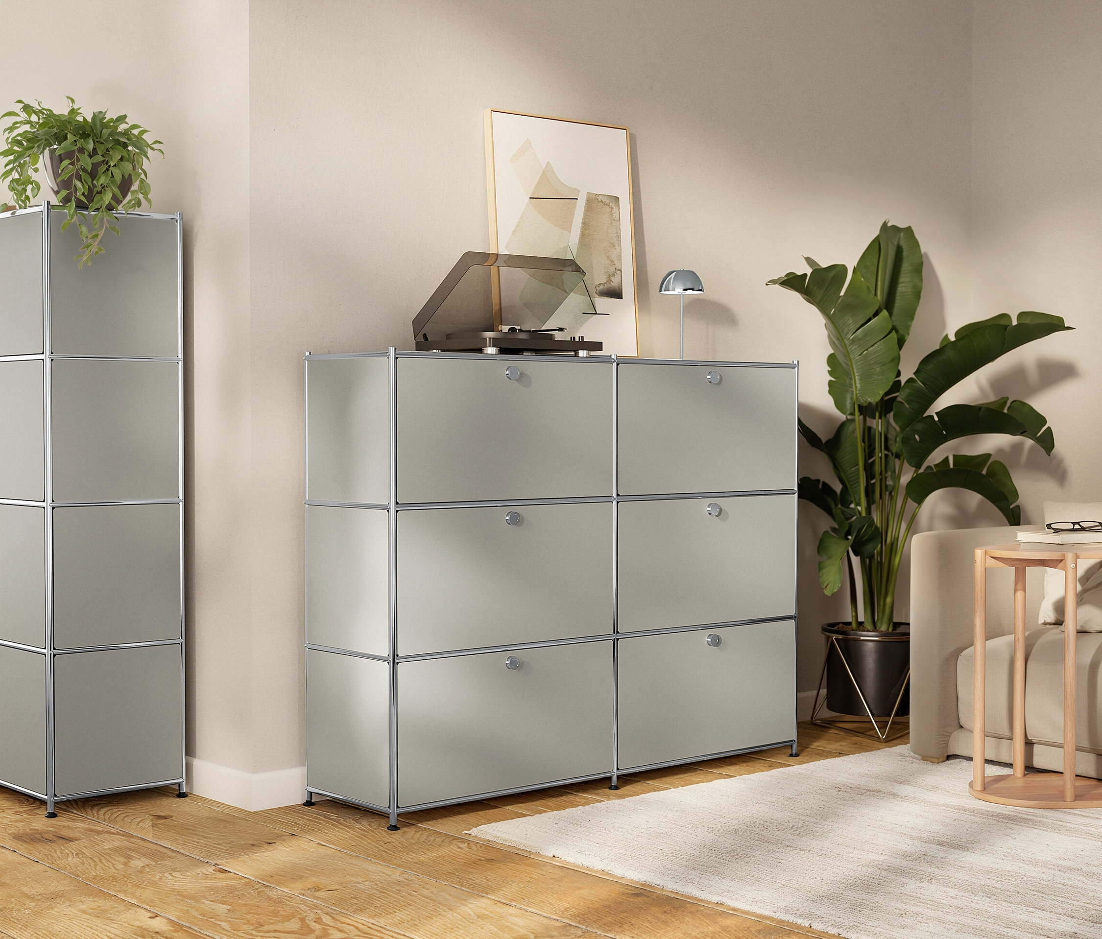 Wohnzimmer mit modularen, grauen Aufbewahrungsschränken, Schallplattenspieler, Zimmerpflanzen und Sofa.