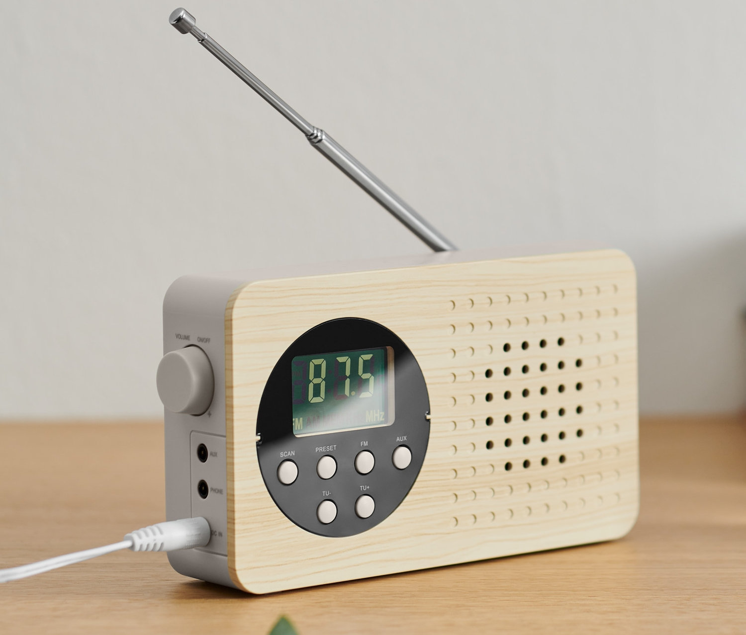 Ein FM-Kompaktradio mit ausziehbarer Antenne steht auf einem Holzschrank.