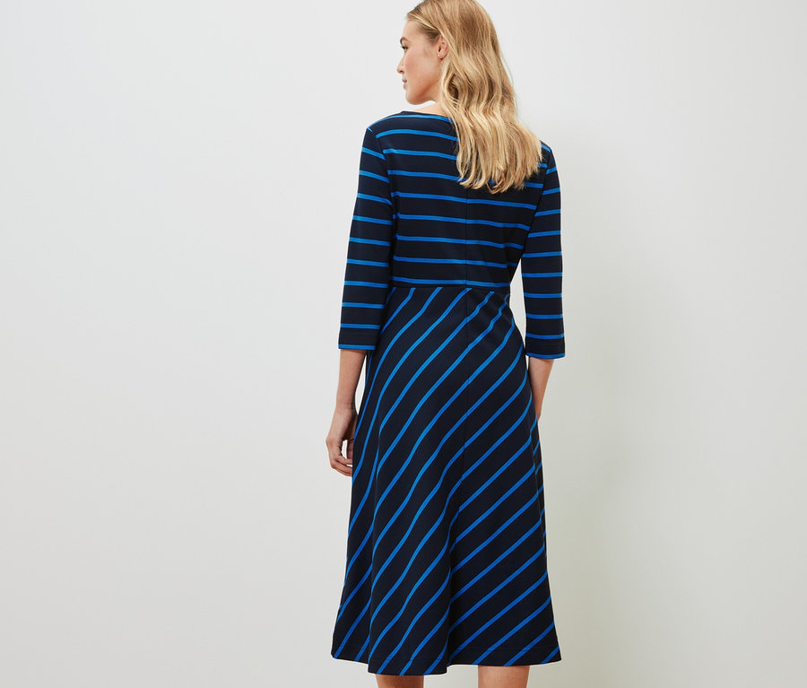 Eine Frau steht mit dem Rücken zur Kamera und trägt ein gestreiftes Jerseykleid.