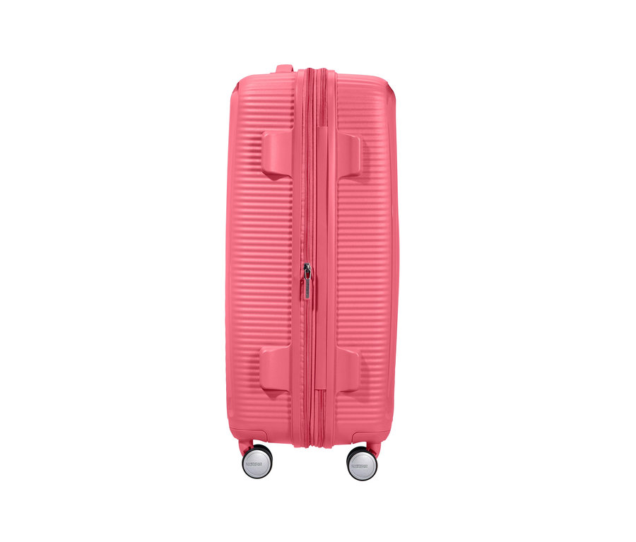 Detailansicht eines mittelgroßen, sonnengeküssten korallenroten American Tourister Hartschalenkoffers »Soundbox« Spinner.