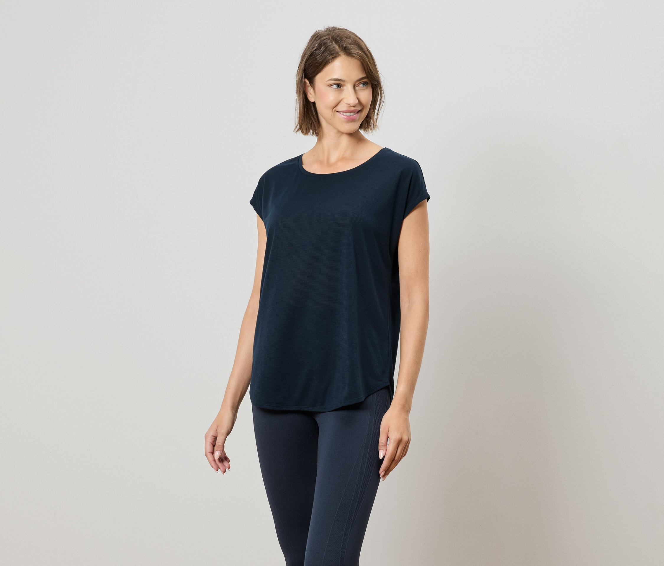 Frau trägt ein marineblaues T-Shirt und marineblaue Leggings.