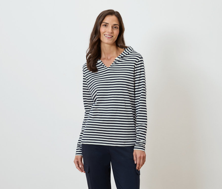 Frau trägt ein gestreiftes langärmeliges Oberteil mit Kapuze und eine marineblaue Hose.