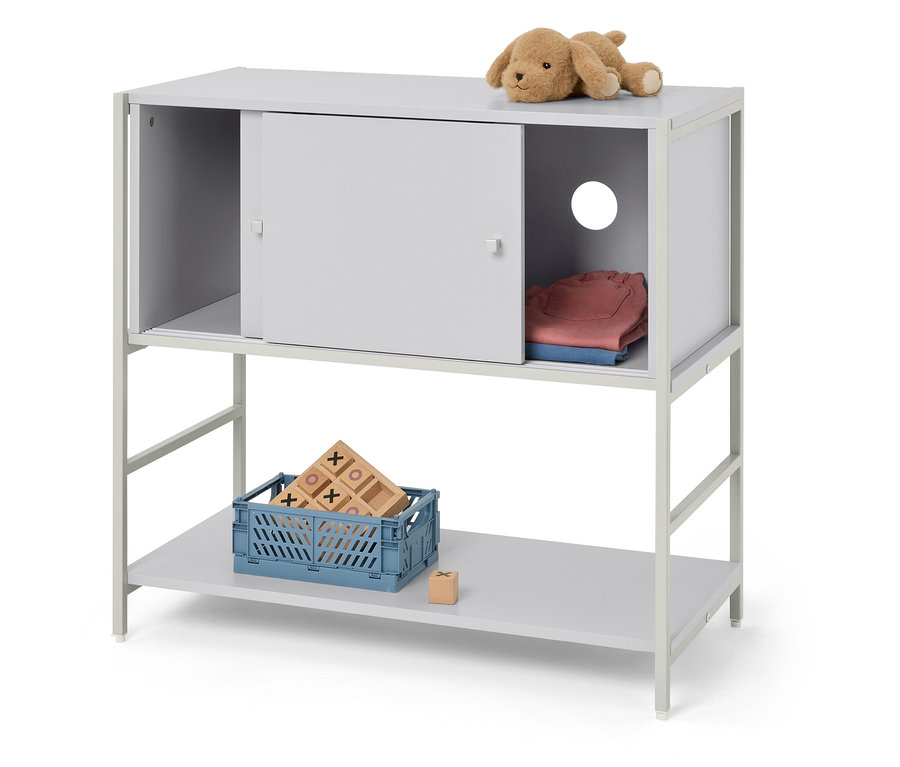 Ein graues Regal mit zwei Ebenen. Auf der oberen Ebene befindet sich ein Stofftier und Kleidung, auf der unteren Ebene eine blaue Kiste mit Spielzeug.