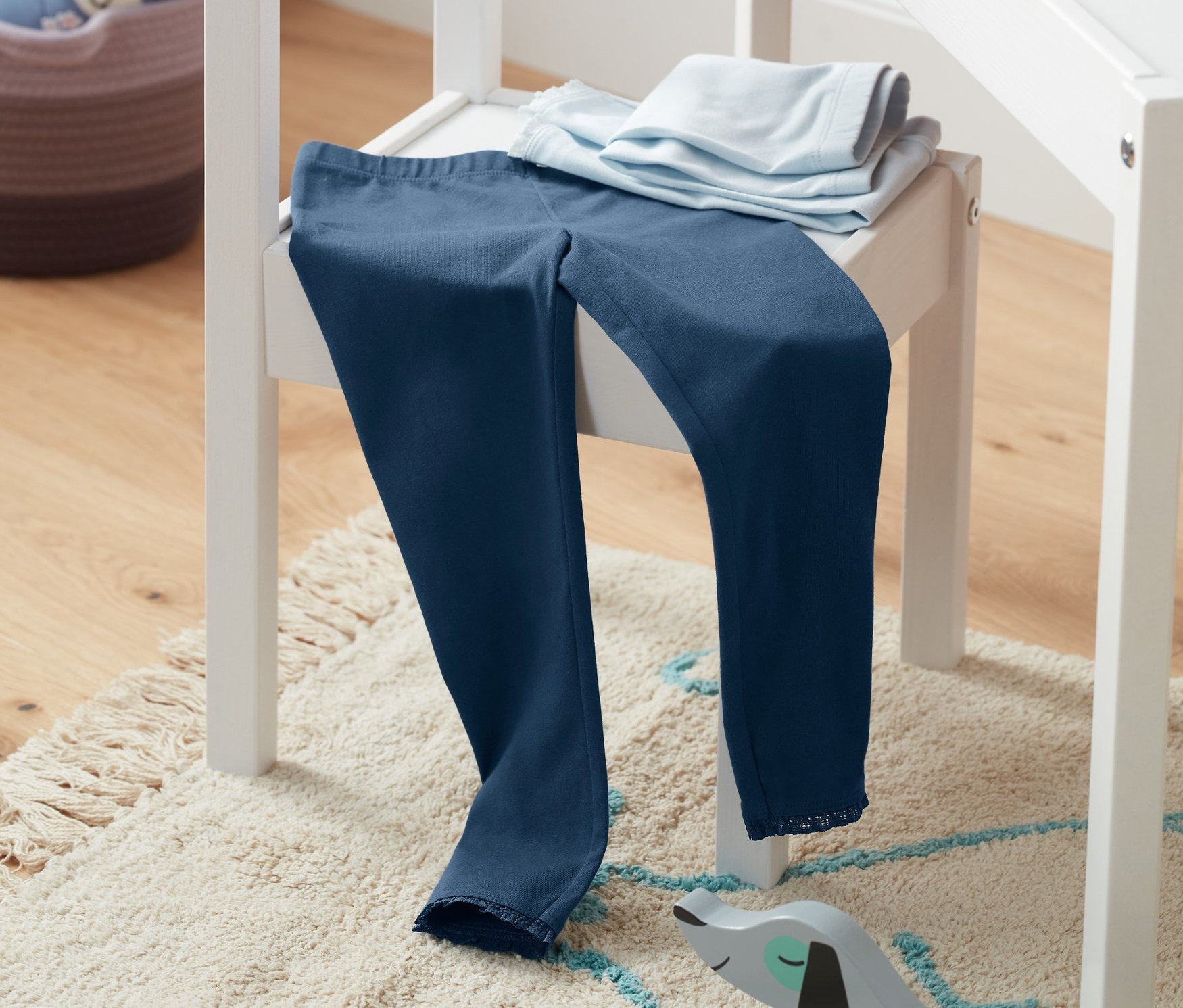 Auf einem weißen Stuhl liegen 2 unifarbene Leggings.