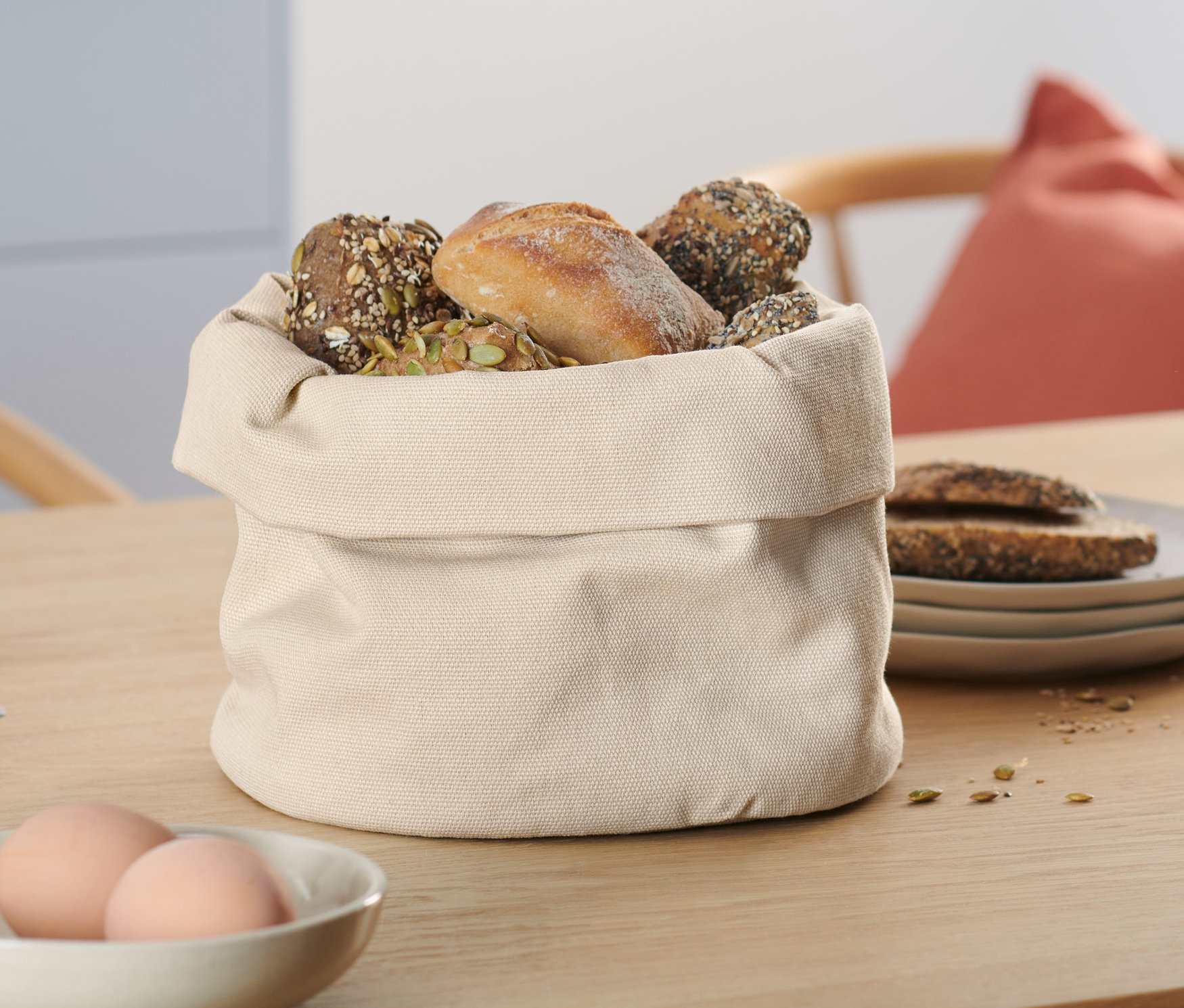 Auf einem Tisch steht ein beiger Brotkorb gefüllt mit Backwaren.