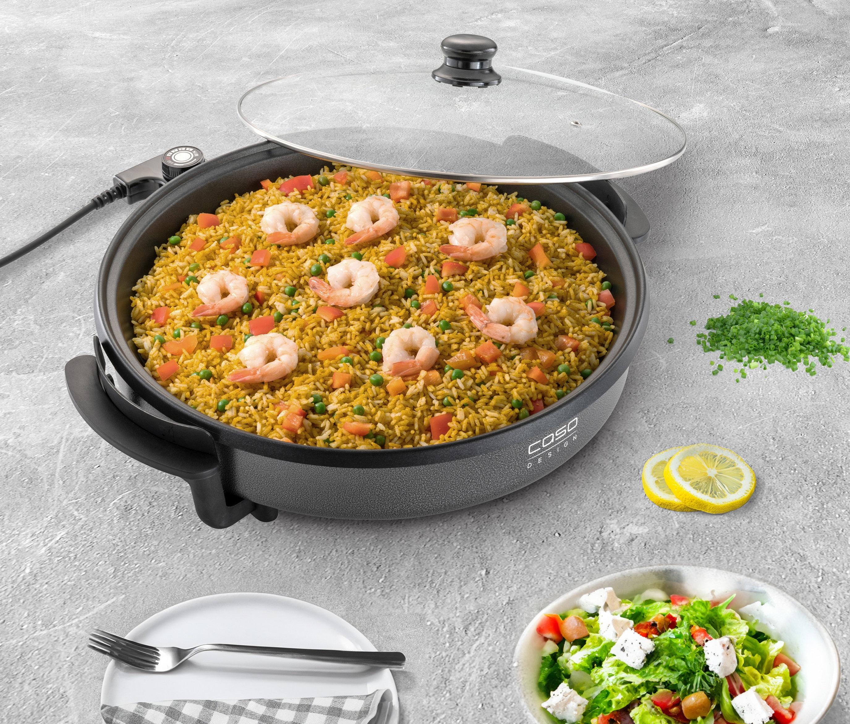 Reis mit Garnelen in der Caso Profi-Partypfanne, dazu Salat, Teller und Zitrone.