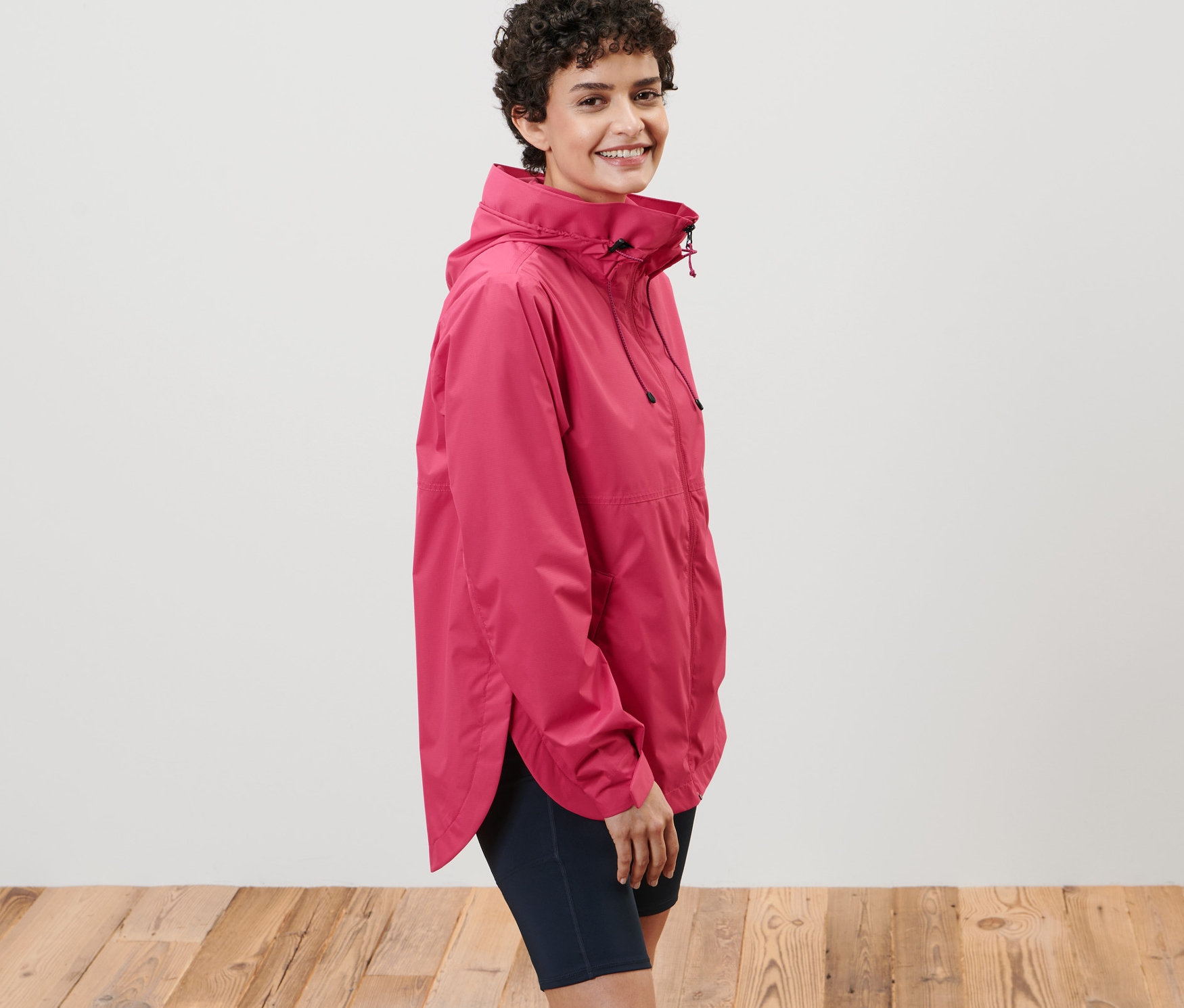 Frau posiert in rosafarbener Regenjacke.