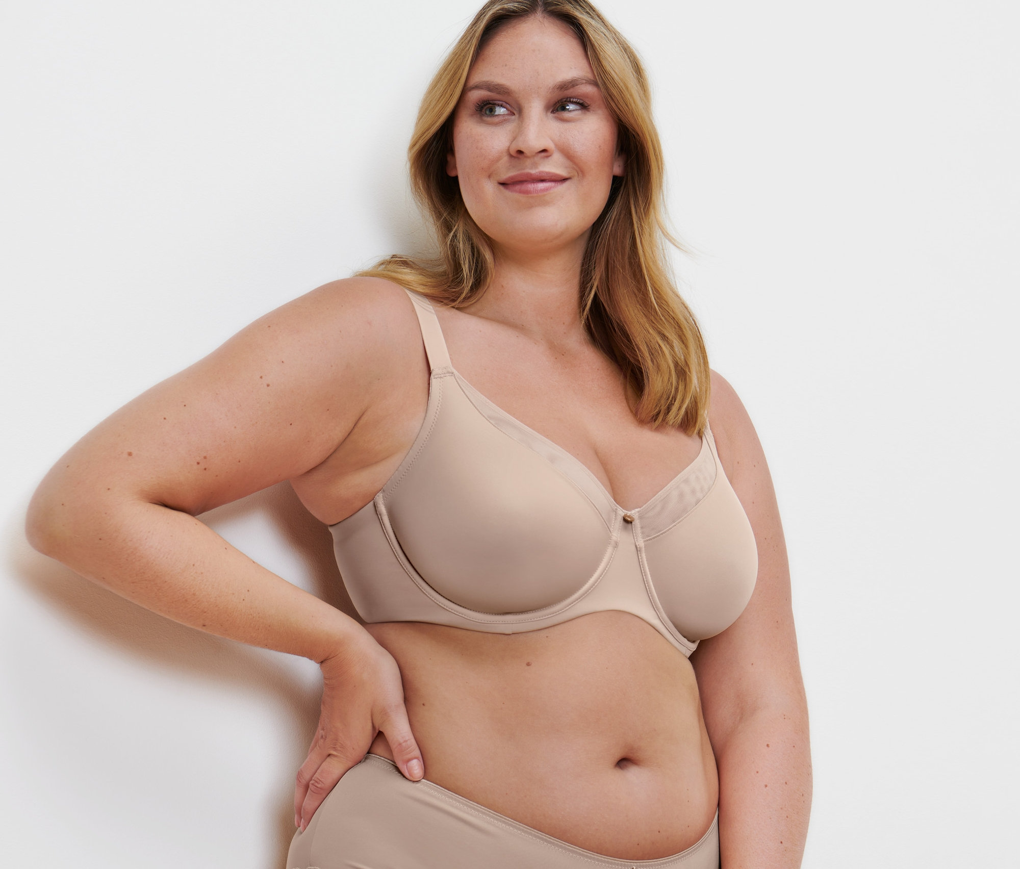 Frau posiert in einem beigen Minimizer-BH.