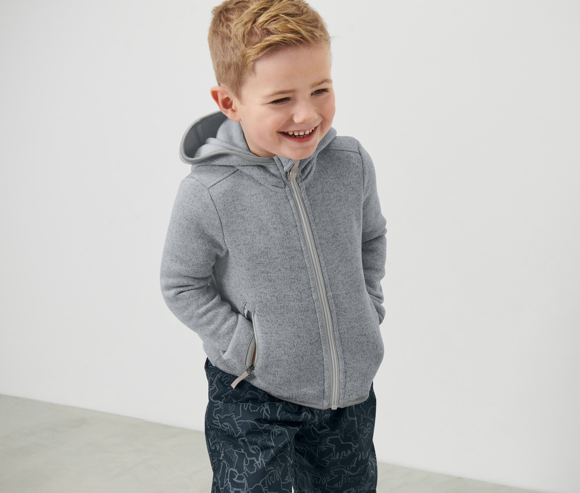Ein lächelnder Junge trägt eine Kinder-Strickfleecejacke.