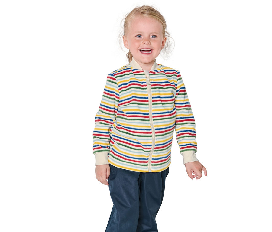Ein lächelndes blondes Mädchen trägt eine gestreifte Jacke und blaue Hosen.