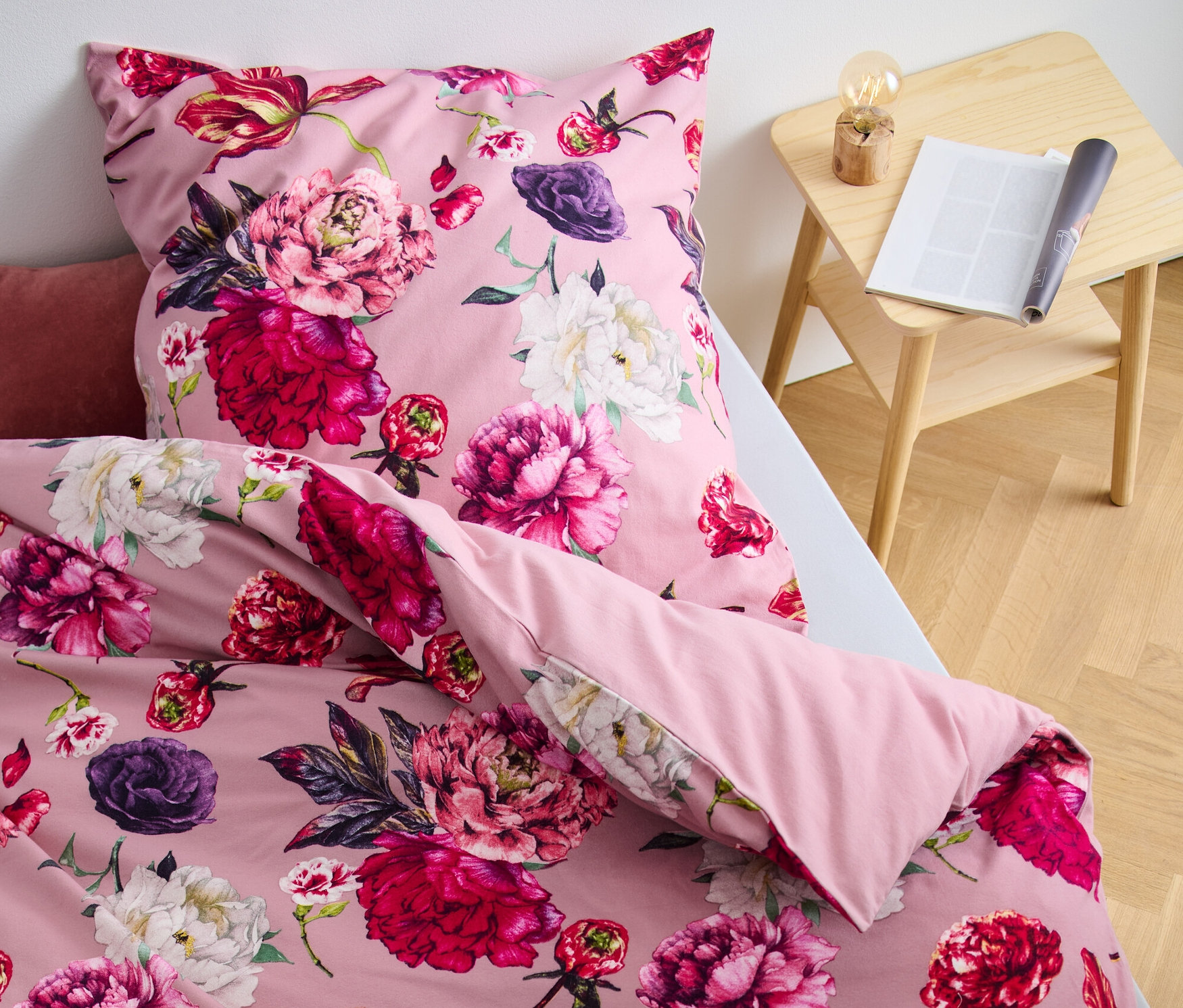 Nahaufnahme von rosa Biber-Bettwäsche mit Blumenmuster auf einem Bett.