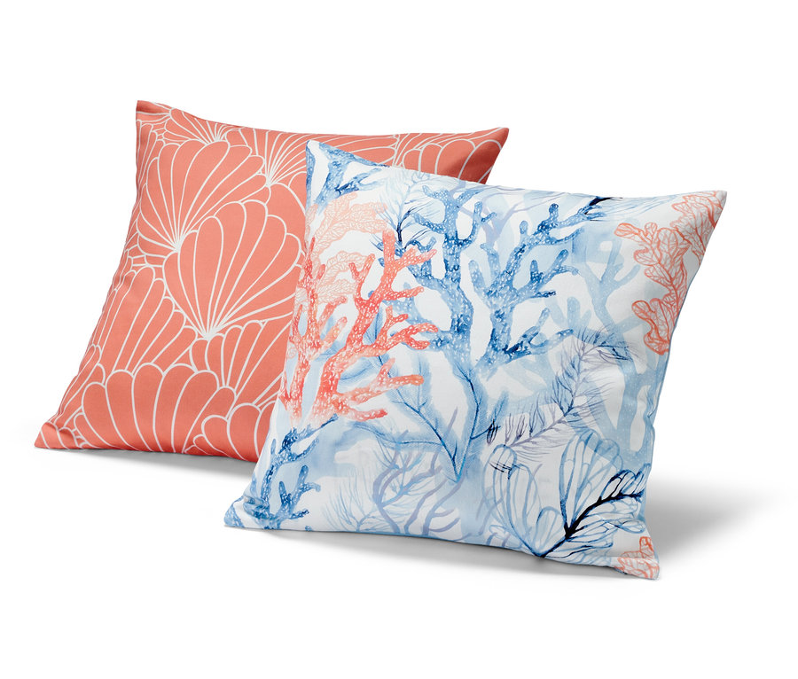 Zwei Dekokissen-Bezüge: Einer korallefarben mit weißem geometrischem Muster, der andere mit blauen und korallefarbenen Korallen.