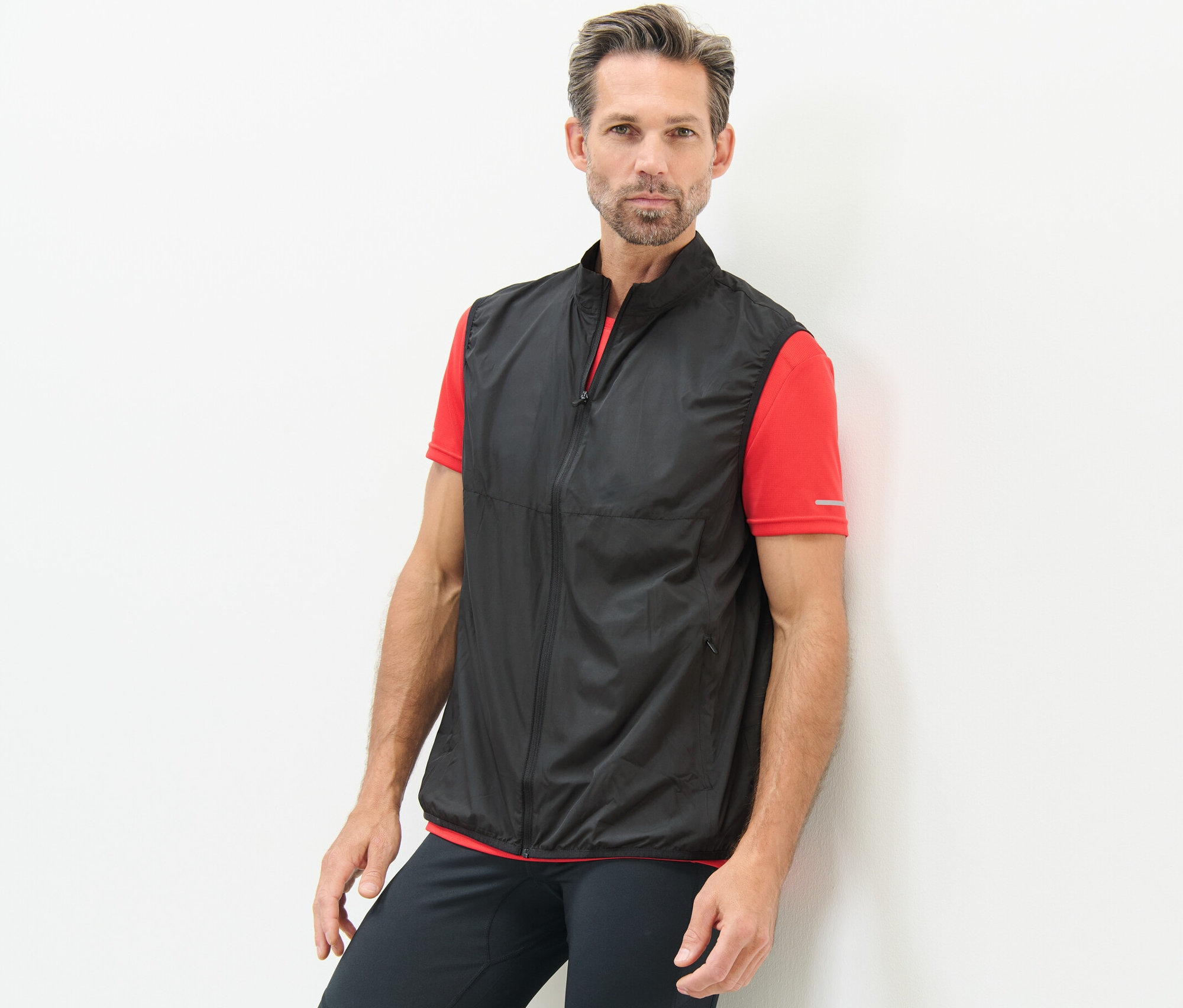 Mann an eine Wand gelehnt, trägt eine Funktionsweste.