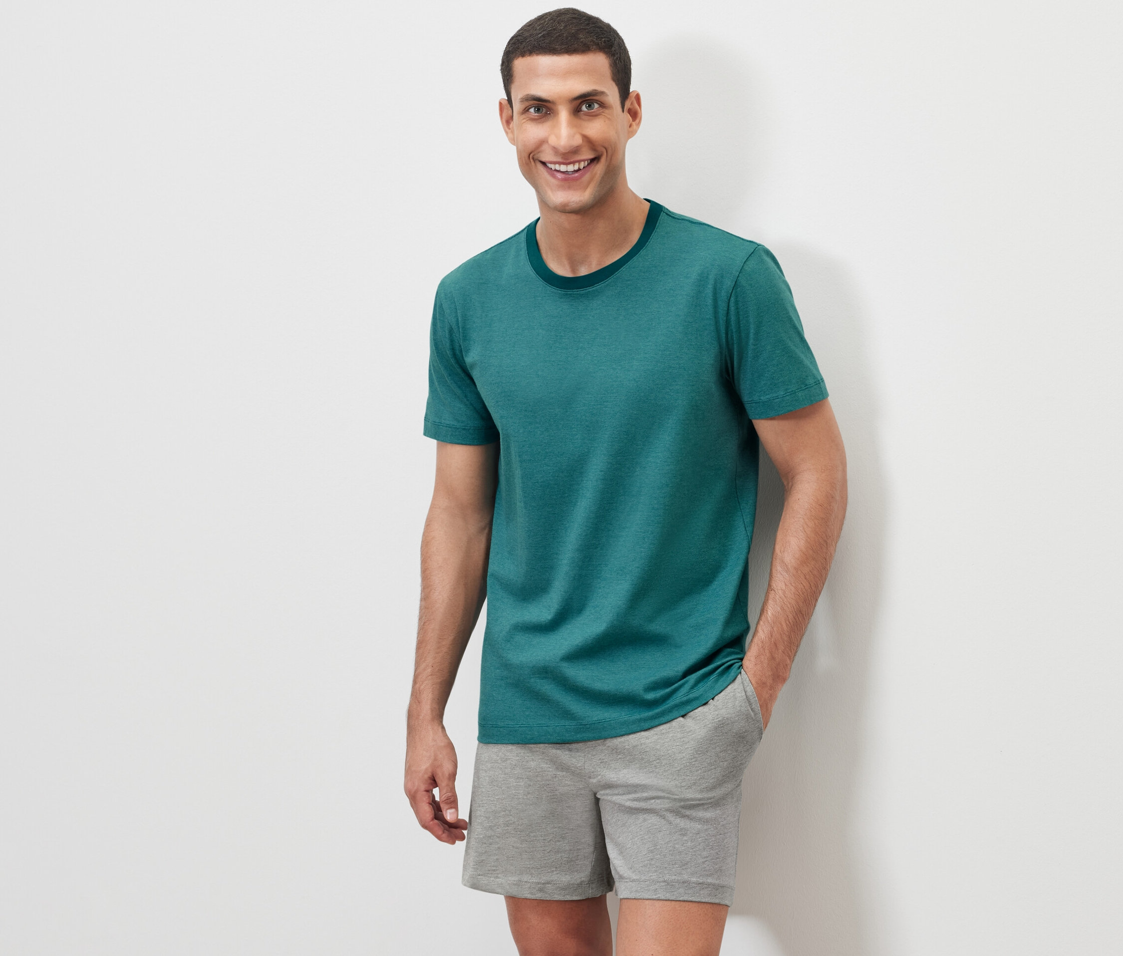 Mann posiert vor weißem Hintergrund im Shorty-Pyjama-Set.