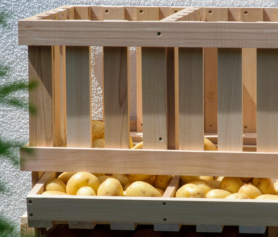 Ein hölzerner Vorratsbehälter gefüllt mit Kartoffeln.