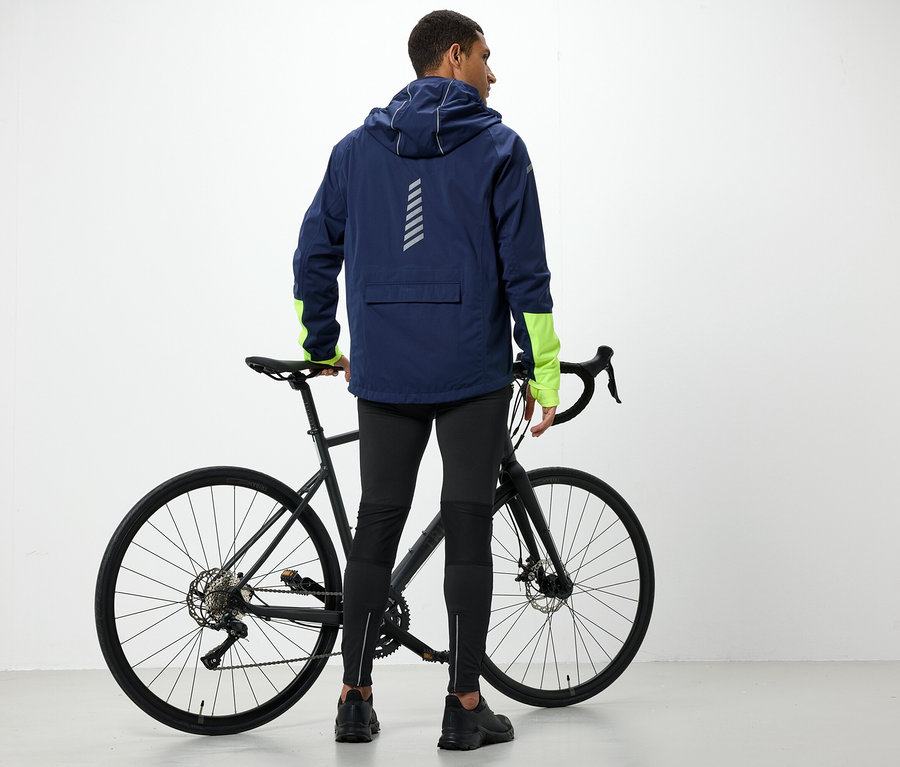 Mann in Kapuzenjacke steht neben Fahrrad.