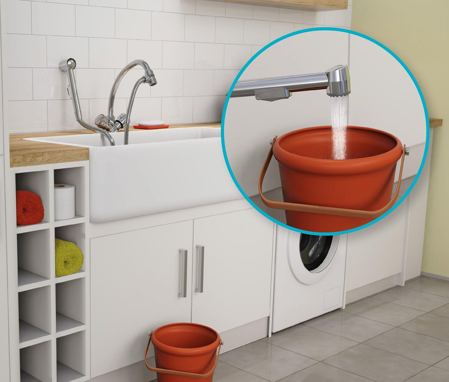 Wasser fließt aus dem Wasserhahn in einen orangefarbenen Eimer in einer weißen Küche.