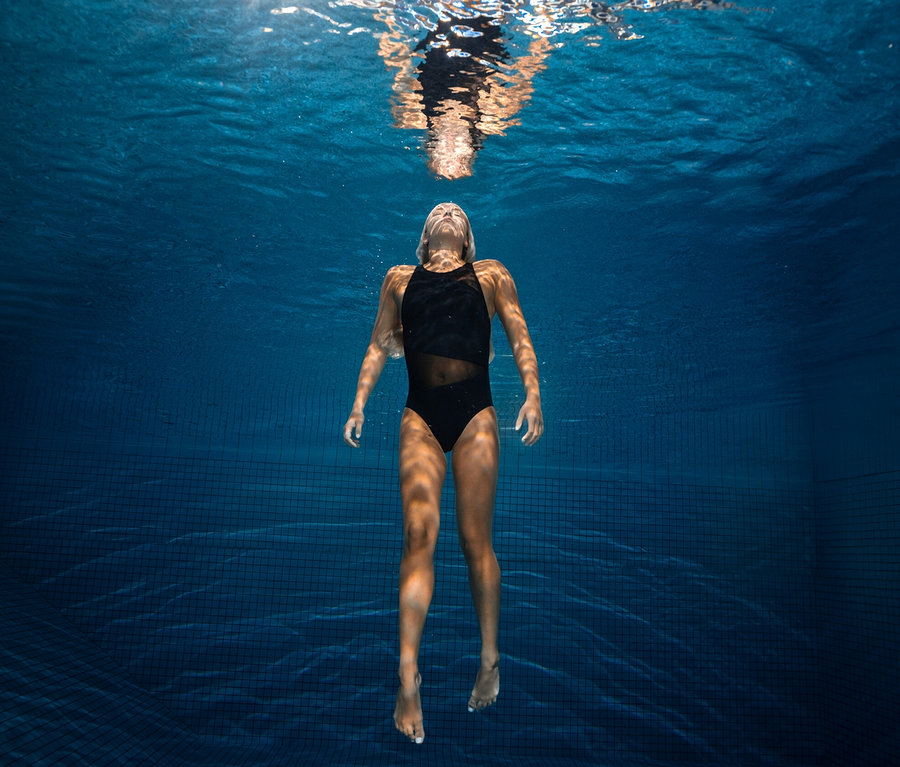 Frau schwimmt im schwarzen arena Feel Damen Badeanzug Mesh Angle Vent Back unter Wasser.