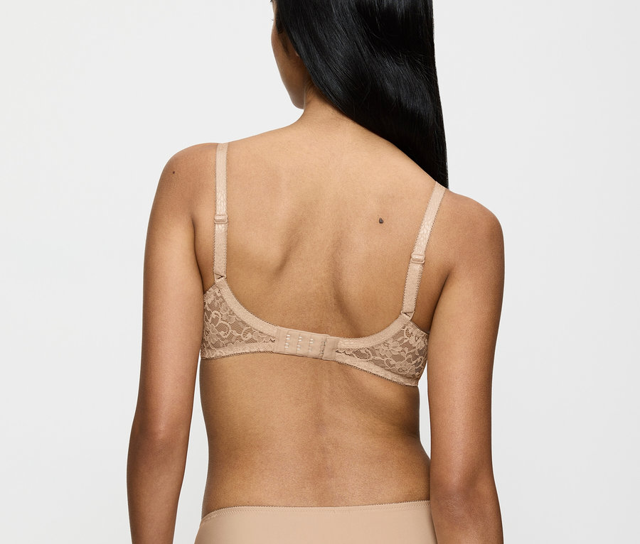 Rückansicht einer Frau mit langen, schwarzen Haaren, die einen beigen Spitzen-BH und Höschen trägt.