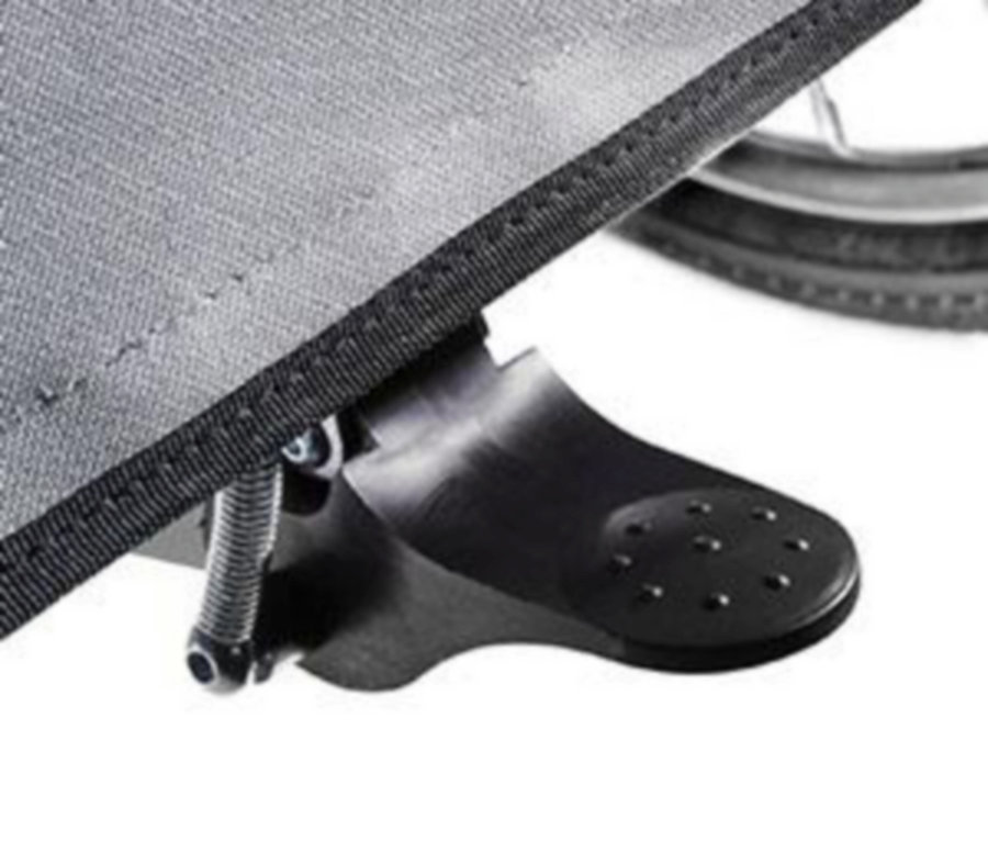 Nahaufnahme einer schwarzen Fußstütze an einem Rollstuhl befestigt, mit einem Teil des Rades im Hintergrund.