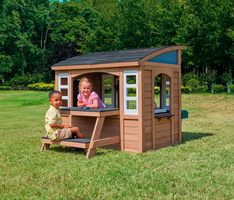 Junge sitzt auf der Bank des Spielhauses Trolli, Mädchen lehnt sich aus dem Fenster des Spielhauses.