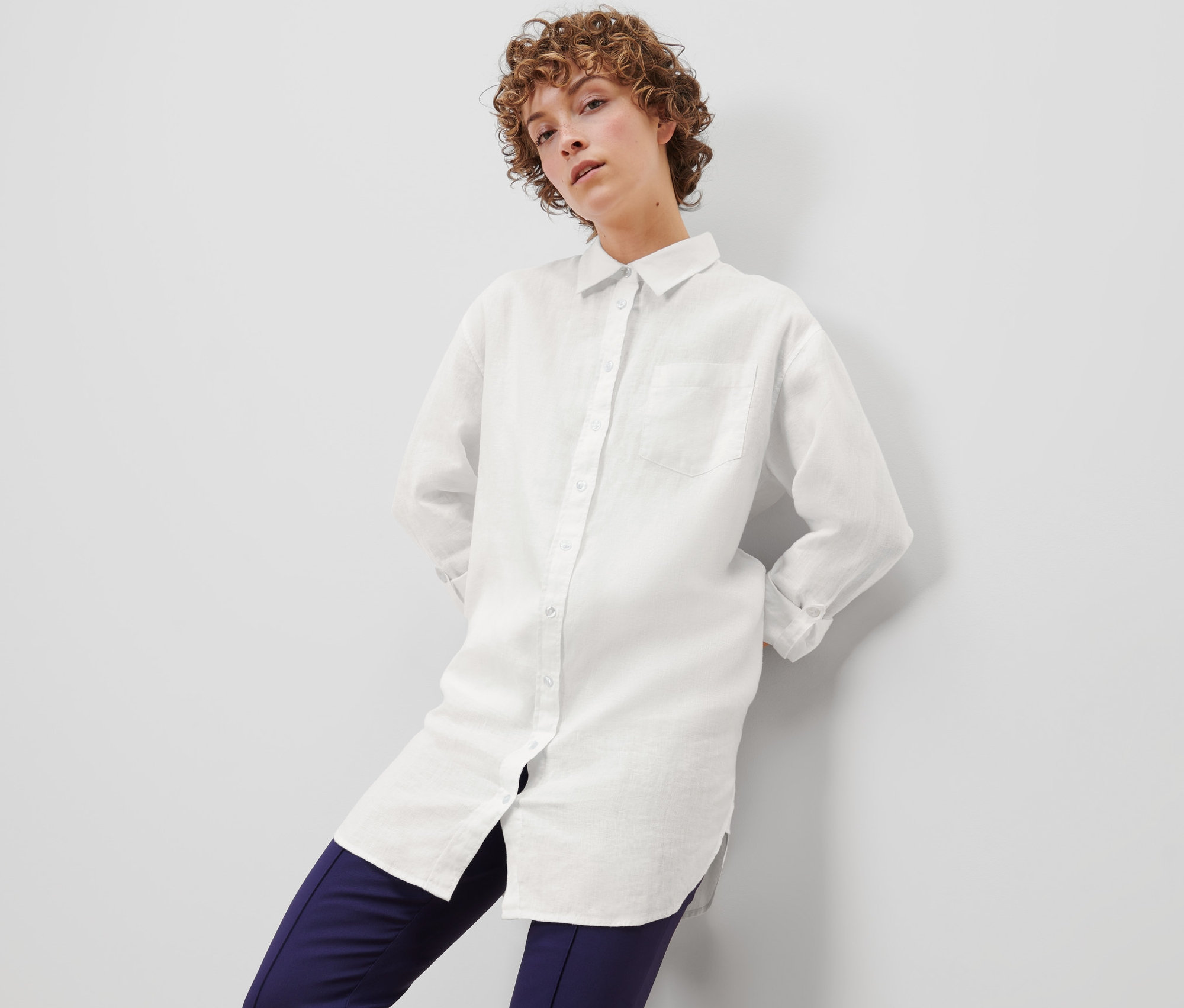 Frau posiert in weißer Leinenbluse.