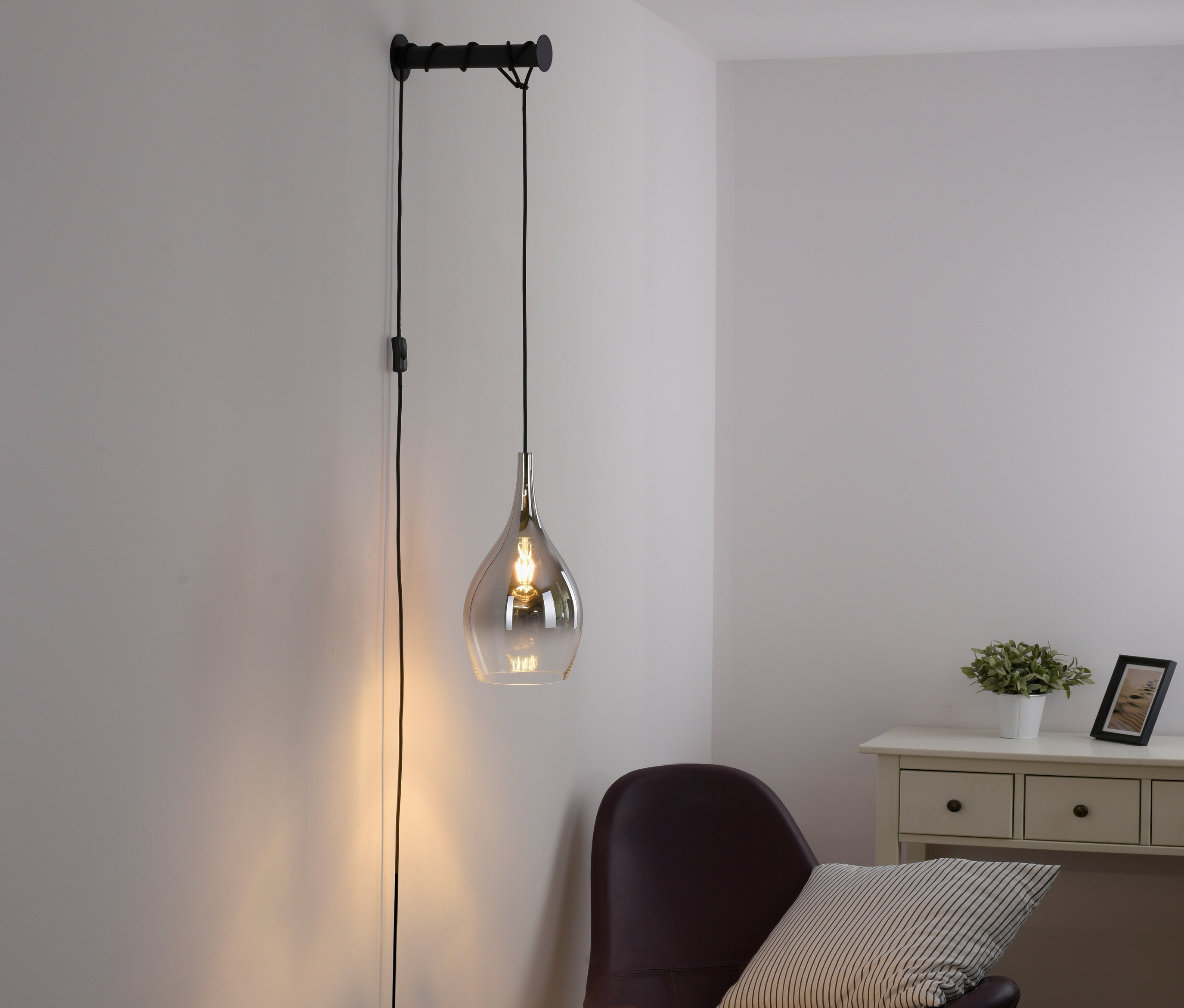 Eine klare Paul Neuhaus Wandleuchte »Pilua« hängt neben einem Sessel.