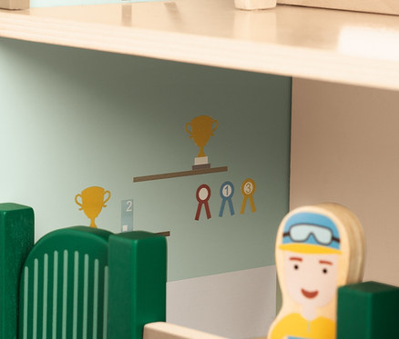 Detailansicht des Pinolino Spielwelt »Reiterhof Lise« Spielzeugs, mit einer hölzernen Reiterin-Figur und Wanddekorationen.