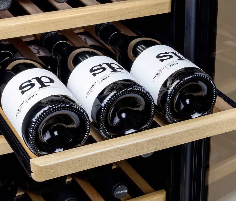 Wein liegt in einem Caso WineClassic Black 24 Weinkühlschrank auf Holzregalen.