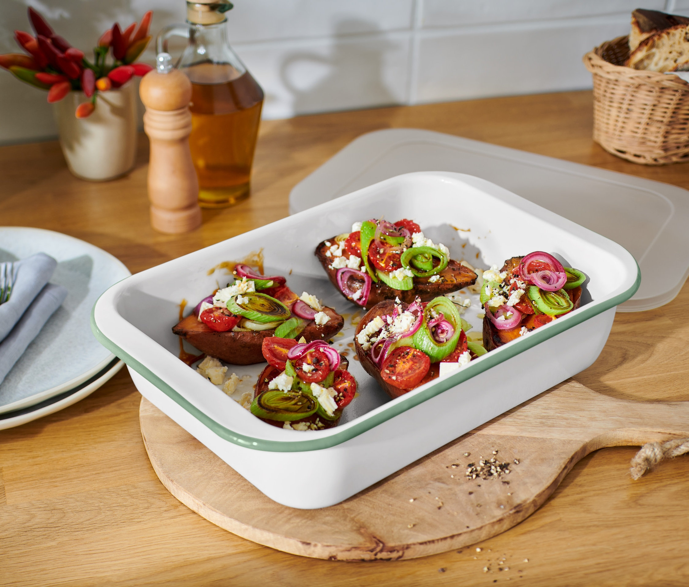 Gebackene Süßkartoffeln mit Tomaten, Zwiebeln und Feta-Käse in einer großen Emaille-Auflaufform mit Deckel.