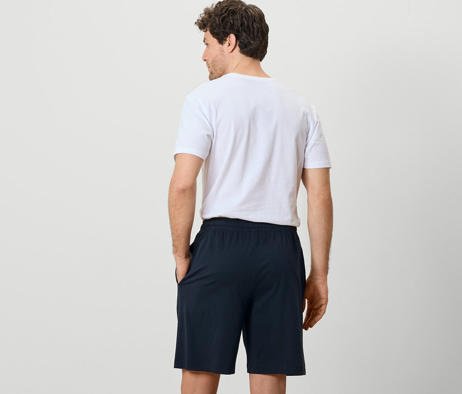 Mann von hinten trägt 2 Pyjamashorts und ein T-Shirt.