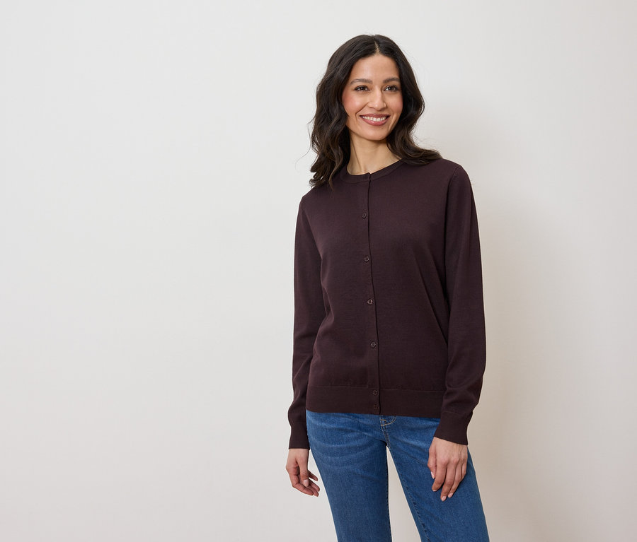 Frau trägt eine dunkelviolette Strickjacke und Jeans.