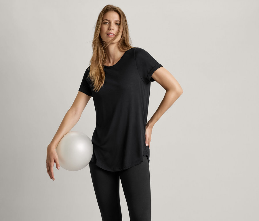 Frau hält einen Ball und trägt ein schwarzes Longshirt.