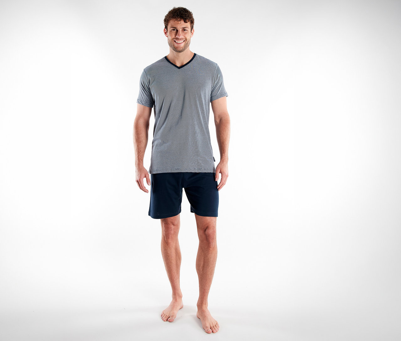 Mann in blauem Tom Tailor Shorty-Pyjama-Set »Nevada«, bestehend aus Shorts und T-Shirt mit V-Ausschnitt.