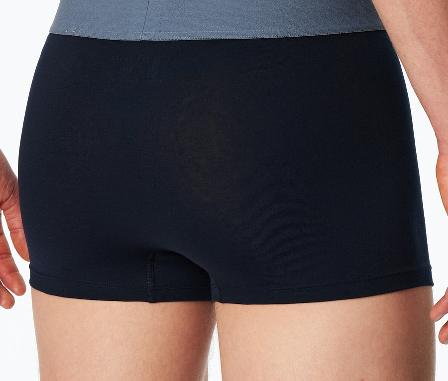 Nahaufnahme der Rückseite eines Mannes, der schwarze Boxershorts mit einem grauen Bund trägt.